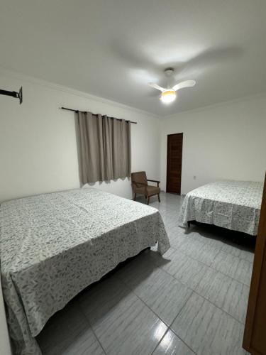 a hotel room with two beds and a chair at Residencial Vilaça in Guarapari