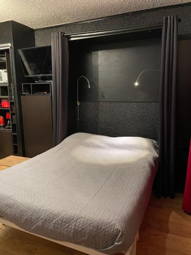 une chambre avec un lit avec une tête de lit noire dans l'établissement La Petite Corneille - a chic and central studio., au Monêtier-les-Bains