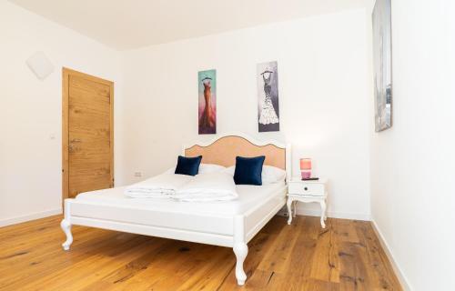 a white bed with blue pillows in a white room at Appartements-Dalila in Sankt Michael im Lungau