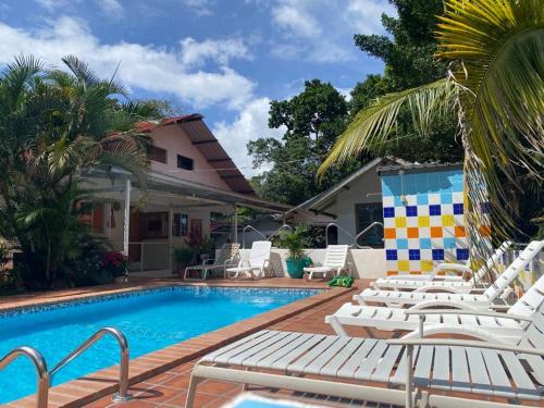 una piscina con tumbonas blancas junto a una casa en Rainforest Yasmin Hotel en Santa Fe