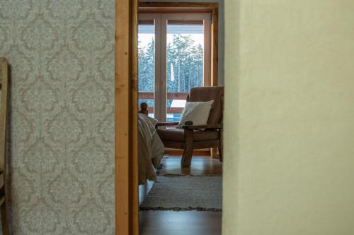 a man sitting in a chair in a living room at Charming Rustic Retreat in Lahemaa National Park in Kolga