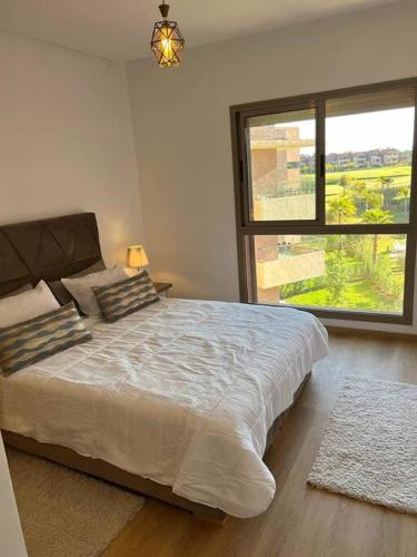 een slaapkamer met een groot bed en een groot raam bij Beautiful apartment in Golf City Marrakech in Marrakesh