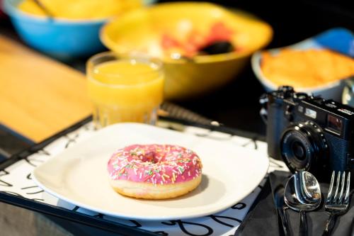 a donut on a plate on a table with a camera at Moxy Edinburgh Fountainbridge in Edinburgh