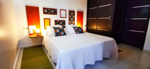 a bedroom with a white bed with pillows on it at Chambres d'hôtes Les Cases BéNaDou in Ngaparou