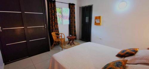 a bedroom with a bed and a chair and a door at Chambres d'hôtes Les Cases BéNaDou in Ngaparou