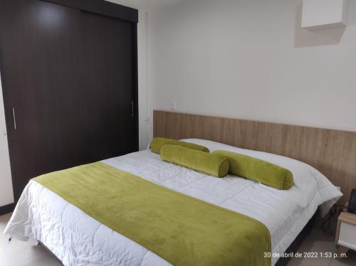 a bed with two green pillows on top of it at Hotel en Rionegro-Rioverde- Apartamento in Rionegro