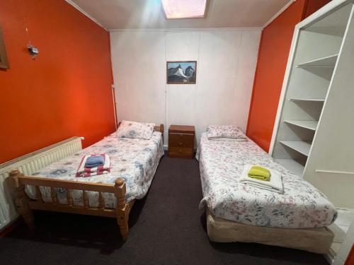two beds in a small room with orange walls at HOSPEDAJE BETTY in Punta Arenas