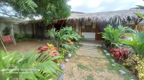 a house with a thatch roof and a yard at Cabaña Riviera Pacific in Pedernales