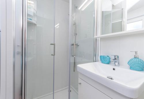 ein weißes Bad mit einem Waschbecken und einer Dusche in der Unterkunft Mobile Home SIMBA in Biograd na Moru