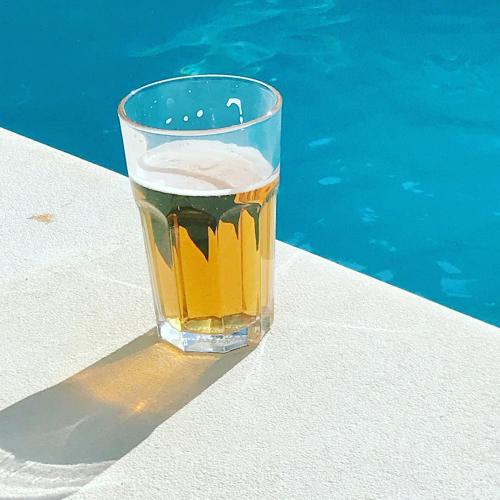 a glass of beer sitting next to a swimming pool at Gîte 1694 - 4 étoiles - proche Futuroscope in Scorbé-Clairvaux