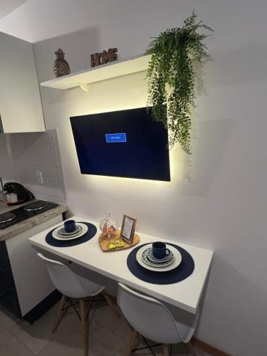 a white table with two plates and a tv on the wall at Studio na Orla in Salvador