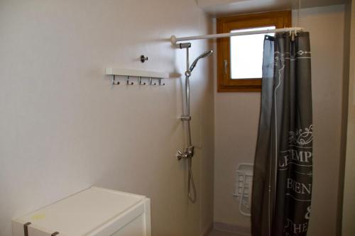 La salle de bains est pourvue d'une douche avec rideau de douche noir. dans l'établissement Appartement 6 places aux pieds des pistes avec piscine, wifi et parking privé PMR, à Orcières
