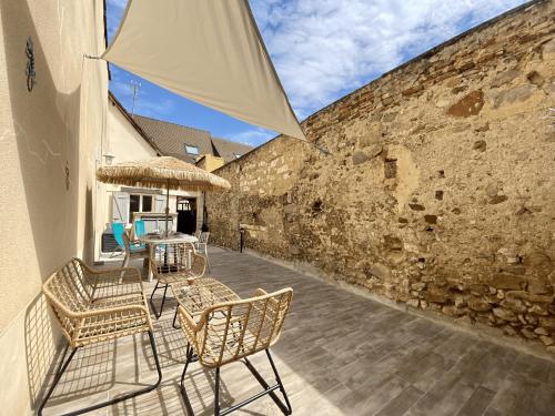 a patio with chairs and a table and a stone wall at Junglissime - By BEST KEYS - Déco Jungle & Grand Patio Privé - 1 chambre séparée & 1 canapé convertible - Centre Ville - Smart TV - Machine à Café Nespresso - WiFi Fibre - Check-in Autonome - Parking Facile & Gratuit in Sens