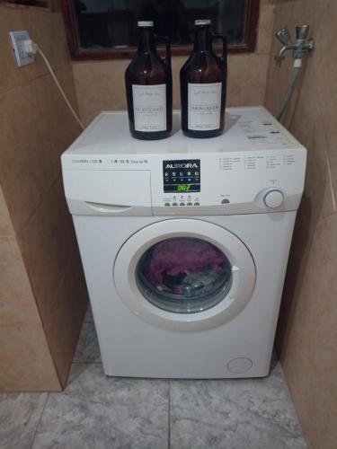 twee flessen wijn bovenop een wasmachine bij Casa para el festival in Colonia Caroya