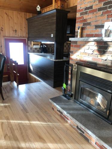 a living room with a fireplace and a kitchen at Le chalet du Golf à Rimouski in Rimouski