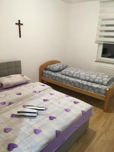 - 2 lits dans une chambre avec une croix sur le mur dans l'établissement Apartman Marija, à Kupres