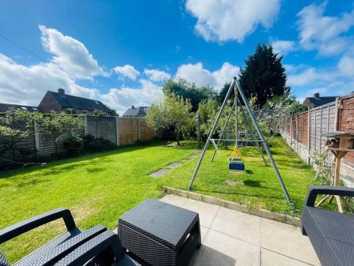 a playground with a swing in a yard at 4 Bedroom Equipped House Driveway- 10 Mins to NEC JLR BHX HS2 & More- Birmingham Sutton Coldfield, Coleshill & More in Solihull