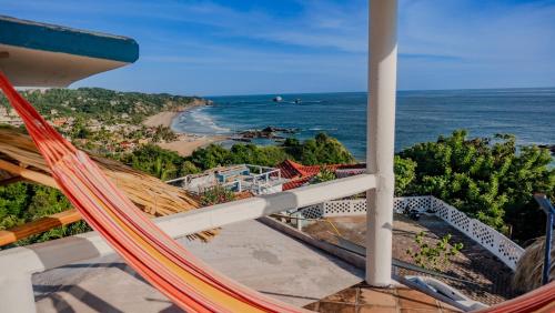 a hammock on a balcony overlooking a beach at Posada Arigalan in Mazunte