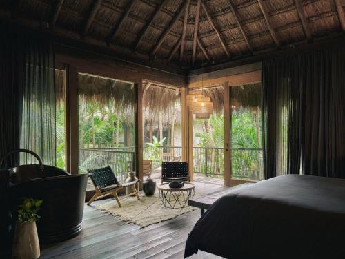 a bedroom with a bed and some chairs and windows at Be Tulum Beach & Spa Resort in Tulum