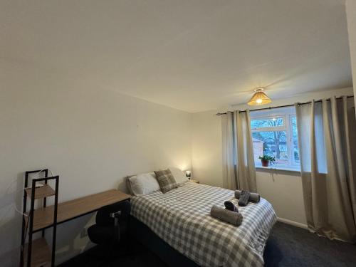 een slaapkamer met een bed met een geruite deken en een raam bij Comfy 2 bedroom house, newly refurbished, self catering, free parking, walking distance to Cheltenham town centre in Cheltenham