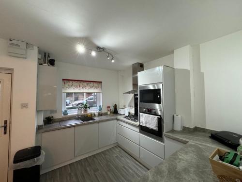 a kitchen with white cabinets and stainless steel appliances at Comfy 2 bedroom house, newly refurbished, self catering, free parking, walking distance to Cheltenham town centre in Cheltenham