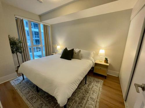 a large white bed in a room with a window at Cozy & charming Downtown condo! in Toronto