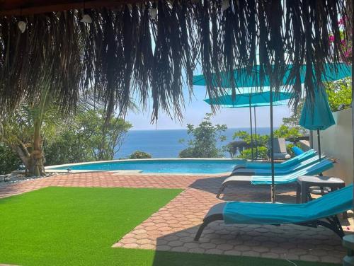 a pool with chairs and umbrellas and the ocean at Casa Sofie Salchi-Tahueca in Cuatunalco