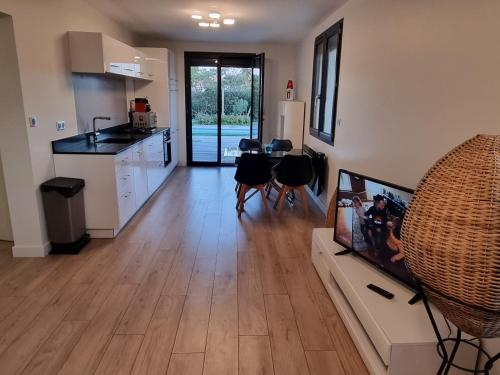 een keuken en woonkamer met een tafel en stoelen bij Bel appartement avec piscine privative à 150m de la plage 6 couchages in Le Barcarès