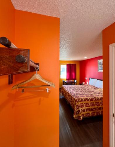 a hotel room with a bed and orange walls at Razorback Inn in Rogers