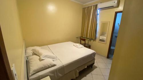 a small bedroom with a bed and a window at Pousada Emaús in Cruzeiro