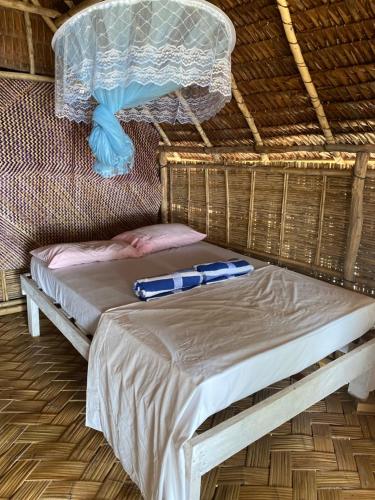een bed in een rieten kamer met een net bij Million Dollar View in Luganville