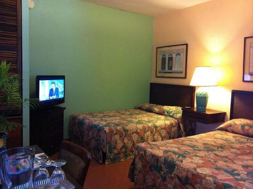 a hotel room with two beds and a flat screen tv at Hotel Iberia - San Juan in San Juan