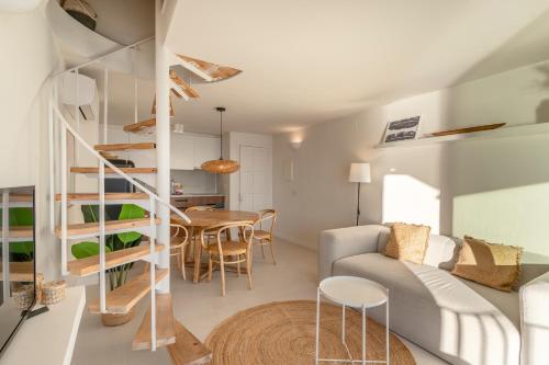 a living room with a spiral staircase and a table at Casa Concha Apartamentos in Calella de Palafrugell