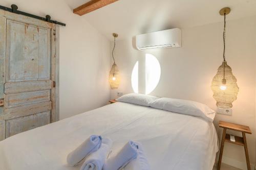a bedroom with a white bed with slippers on it at Casa Concha Apartamentos in Calella de Palafrugell