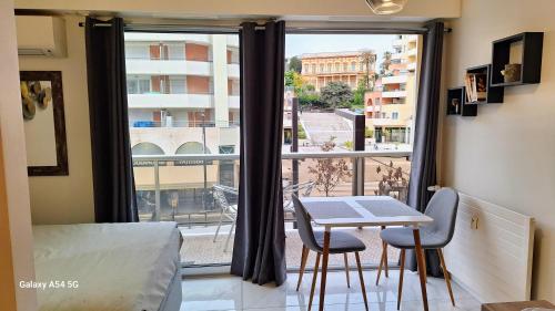 Pokój ze stołem i krzesłami oraz dużym oknem w obiekcie Cosy Studio 200 m from Nice Beach & Promenade des Anglais w Nicei