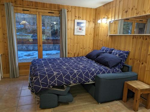 a bedroom with a bed and a chair and a window at Appartement Cosy avec Terrasse et Garage in Les Houches