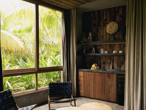 a kitchen with a large window and a table and chairs at BE Destination Tulum in Tulum