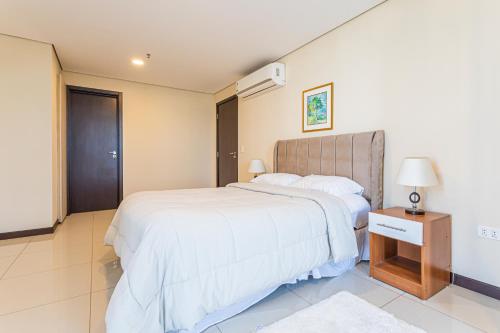 Un dormitorio con una gran cama blanca y una mesita de noche. en Spacious & unbeatable location, en Asunción