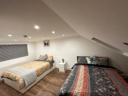 Lovely Hillingdon Family Holiday Home - 7 bedrooms في Ickenham: غرفة نوم بسريرين في العلية