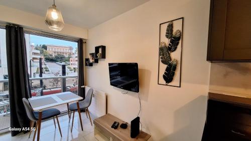 ein Wohnzimmer mit einem Tisch und einem TV an der Wand in der Unterkunft Cosy Studio 200 m from Nice Beach & Promenade des Anglais in Nizza