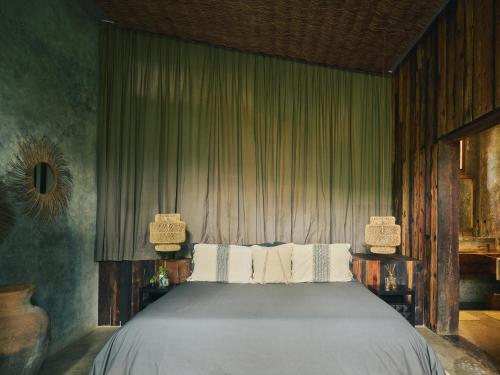 a bed in a bedroom with green curtains at BE Destination Tulum in Tulum