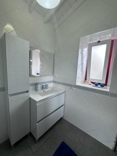 ein weißes Badezimmer mit einem Waschbecken und einem Kühlschrank in der Unterkunft Cantinho dos Cagarros in Lajes do Pico