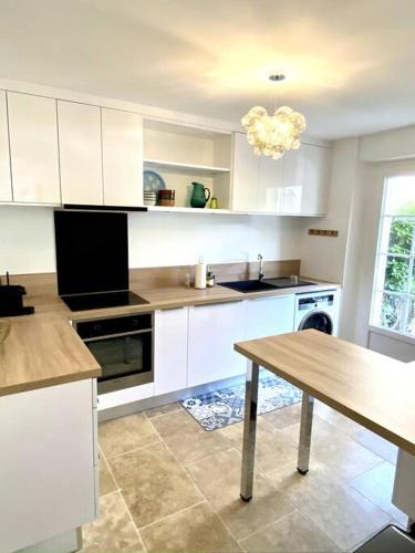 une cuisine avec des armoires blanches et une table en bois dans l'établissement Les Terrasses des Antiques, à Saint-Rémy-de-Provence