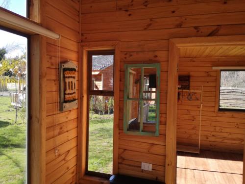 a log cabin with two windows and a porch at Rukawe Quillon in Quillón
