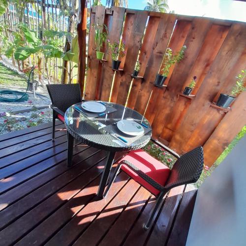 une table et des chaises en verre sur une terrasse en bois dans l'établissement Nuutea lodge, à Avatoru