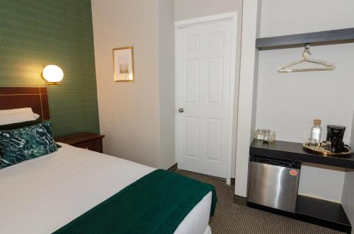 a hotel room with a bed with a green blanket at Hotel Dorion in Montréal