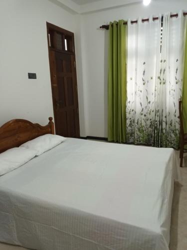 una camera con letto bianco e tende verdi di White's vila home a Matara