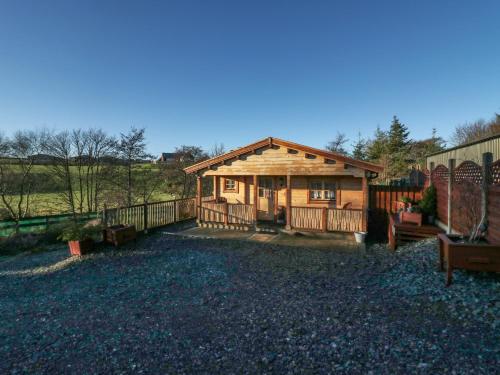 a log cabin with a porch and a fence at Ballinorig Lodge in Cleator Moor