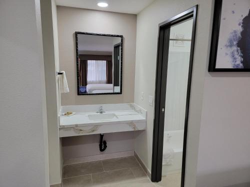 a bathroom with a sink and a mirror at Travelodge by Wyndham Buena Park in Buena Park