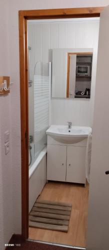 une salle de bain blanche avec un lavabo et un miroir dans l'établissement Appartement Valfrejus Les Melezets1 21m2 centre station, à Modane